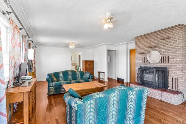 living area featuring a brick fireplace, ceiling fan, and wood finished floors