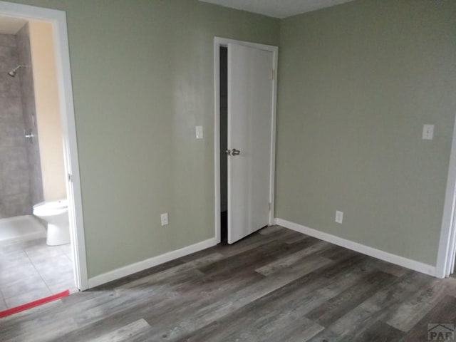 unfurnished bedroom featuring baseboards and dark wood-type flooring