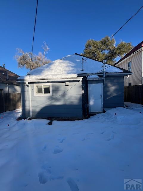 snow covered garage with fence