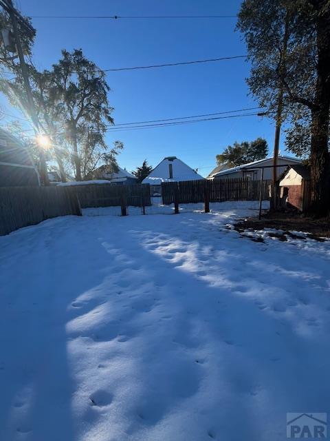 yard covered in snow featuring fence