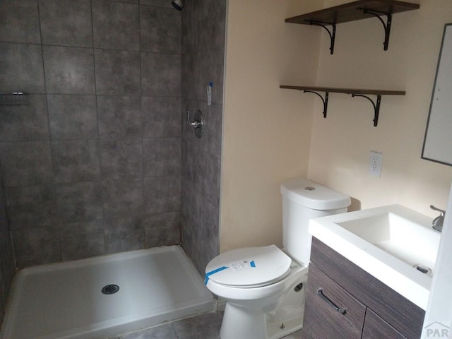 bathroom with tiled shower, vanity, toilet, and tile patterned floors