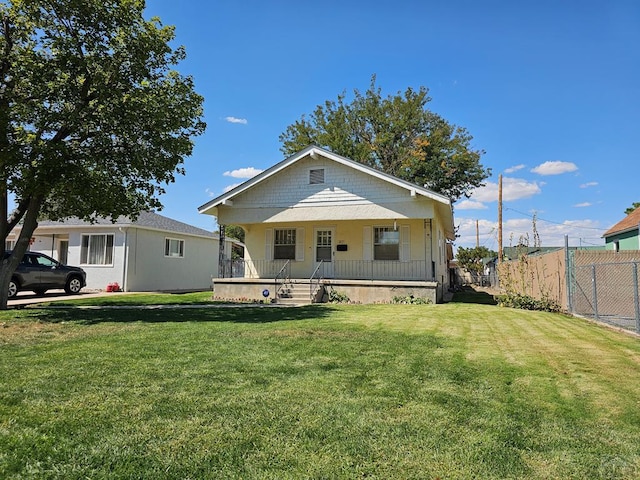 bungalow with a porch, fence, and a front lawn