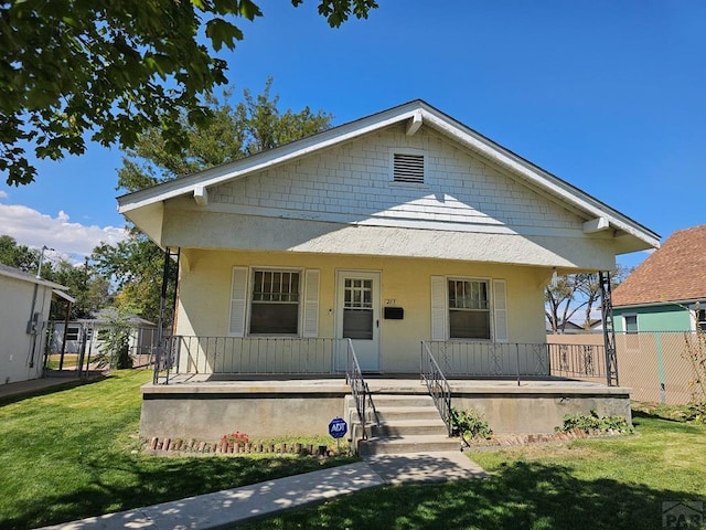 bungalow featuring a porch, a front lawn, and stucco siding