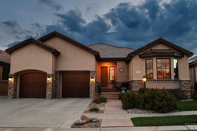 view of front facade featuring a tile roof, stucco siding, concrete driveway, an attached garage, and stone siding