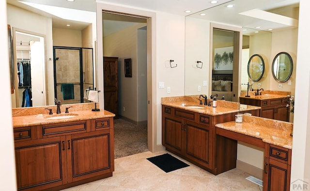 ensuite bathroom with two vanities, a sink, and a walk in closet