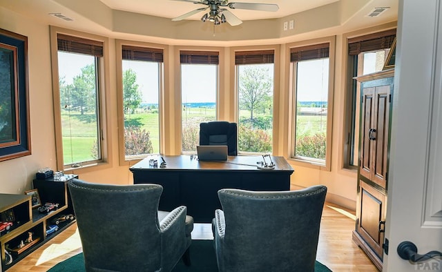 home office featuring light wood finished floors, visible vents, and a ceiling fan