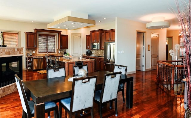 dining area with a tiled fireplace, dark wood-type flooring, and recessed lighting