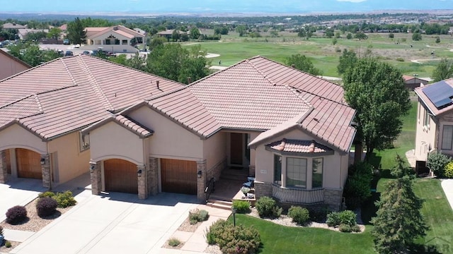 view of front facade featuring stone siding, a tiled roof, concrete driveway, and stucco siding