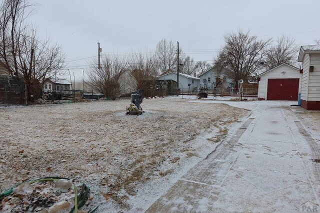 view of yard featuring a detached garage, an outdoor structure, fence, and a residential view