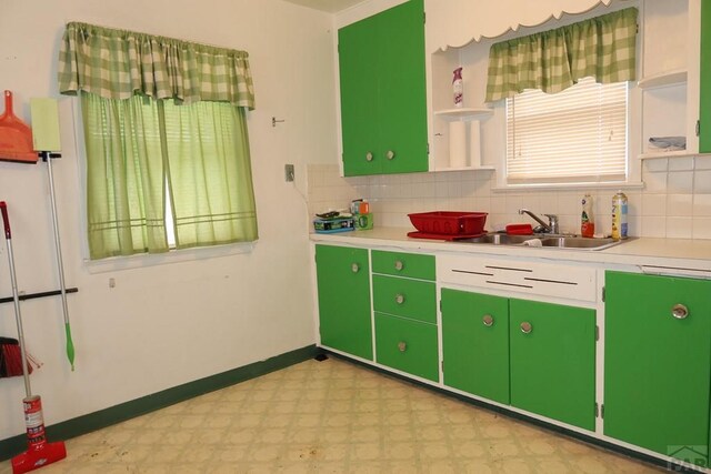 kitchen featuring open shelves, a sink, light countertops, light floors, and green cabinetry