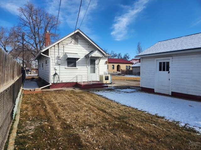 back of house featuring a yard, fence, and a chimney