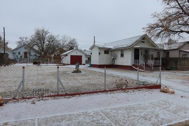 bungalow-style home featuring a garage, a fenced front yard, and an outbuilding