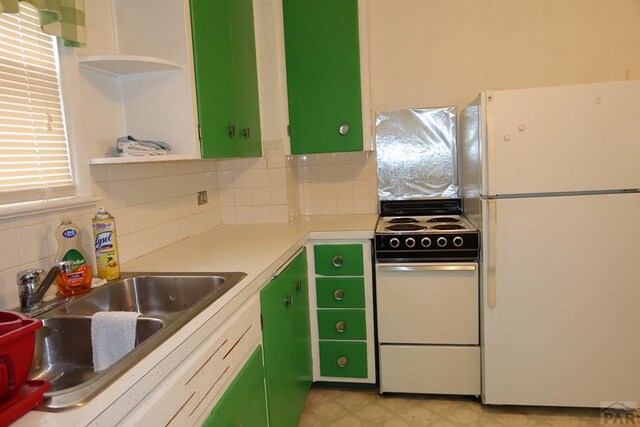 kitchen featuring open shelves, light countertops, a sink, white appliances, and green cabinetry