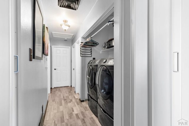 laundry area featuring visible vents, light wood-style flooring, washing machine and dryer, attic access, and laundry area