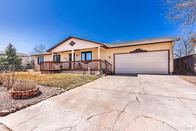 ranch-style house featuring concrete driveway, a garage, fence, and covered porch