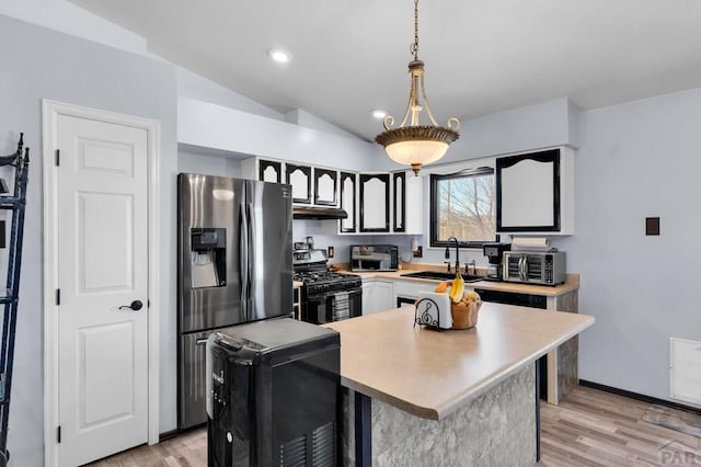 kitchen with under cabinet range hood, light countertops, gas range oven, light wood-style floors, and a sink