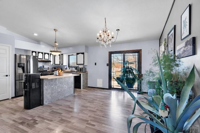 kitchen with light wood-style flooring, a center island, appliances with stainless steel finishes, light countertops, and a chandelier