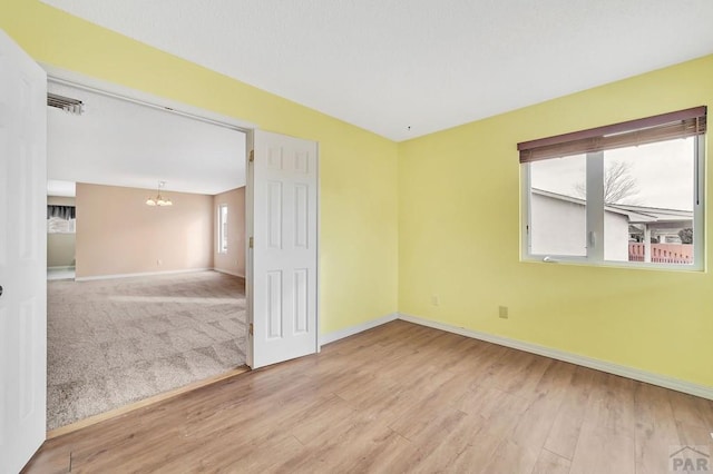 unfurnished room featuring baseboards, plenty of natural light, a chandelier, and wood finished floors