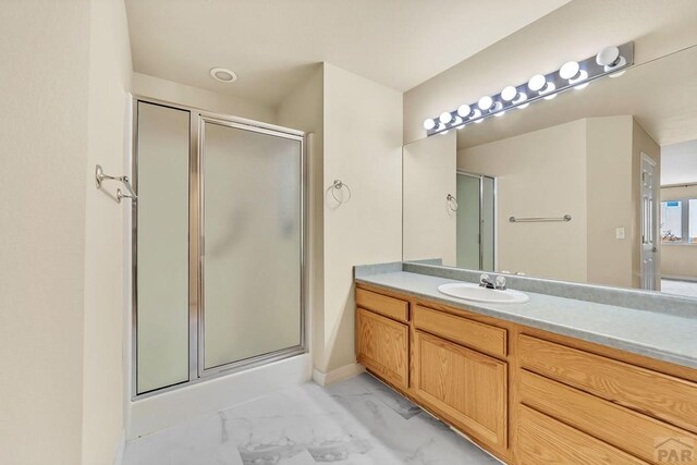 bathroom with marble finish floor, a shower stall, and vanity