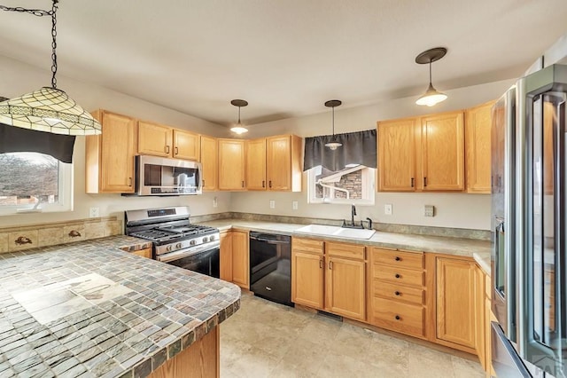 kitchen with appliances with stainless steel finishes, light brown cabinets, a sink, and hanging light fixtures