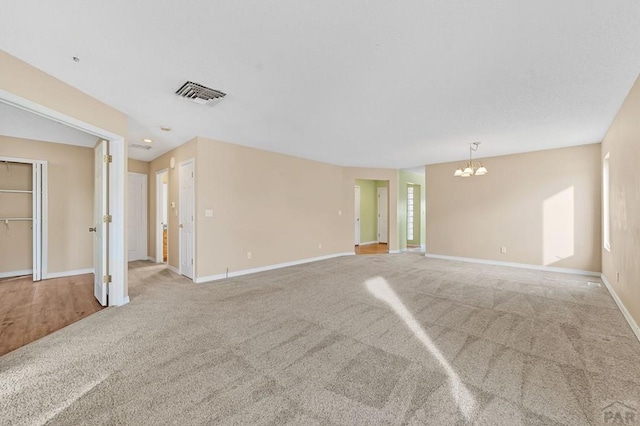 empty room featuring carpet, visible vents, and baseboards