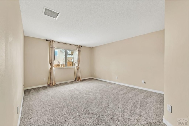 carpeted empty room featuring baseboards, visible vents, and a textured ceiling