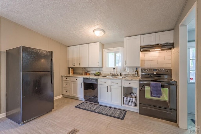 kitchen with under cabinet range hood, a sink, white cabinets, decorative backsplash, and black appliances