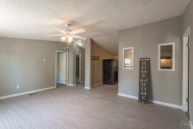 unfurnished room featuring visible vents, a textured ceiling, wood finished floors, and a ceiling fan