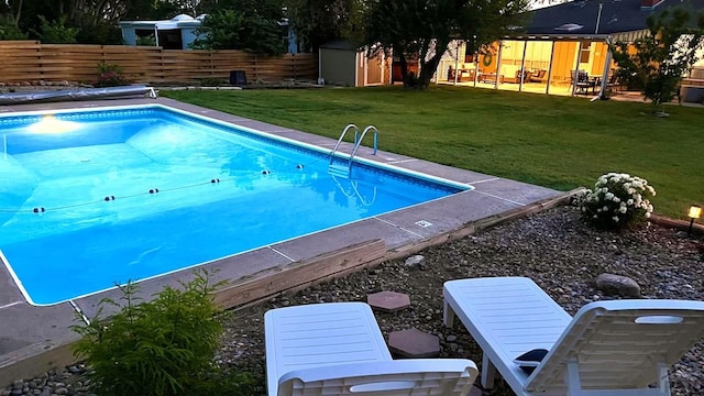 view of swimming pool with a storage shed, a yard, an outdoor structure, and a fenced backyard