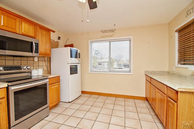 kitchen featuring light countertops, appliances with stainless steel finishes, backsplash, and baseboards