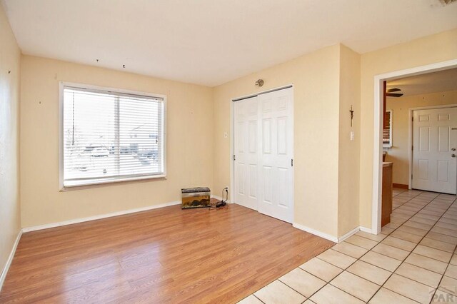 unfurnished bedroom with a closet, light wood-style flooring, and baseboards