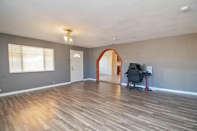 interior space with arched walkways, wood finished floors, and baseboards