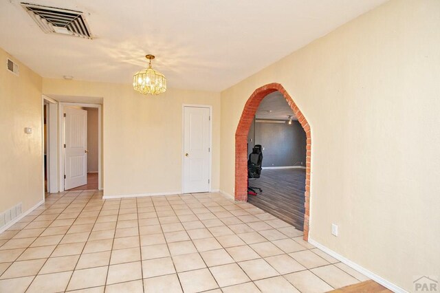 empty room with visible vents, an inviting chandelier, and light tile patterned flooring