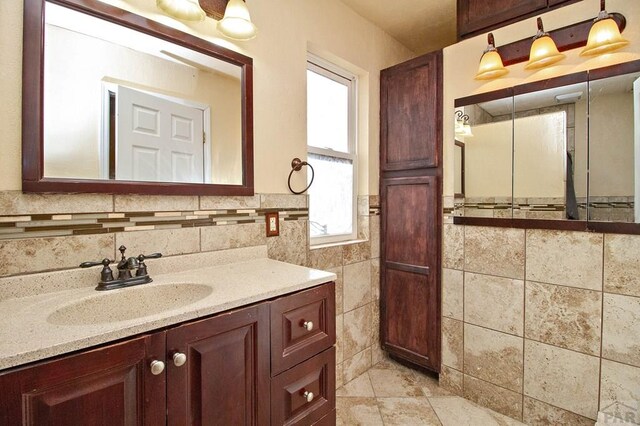 bathroom featuring wainscoting, tile walls, and vanity