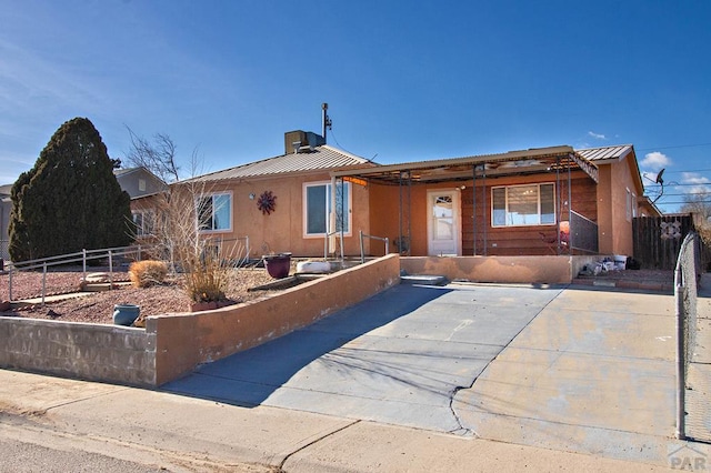 ranch-style home with a standing seam roof, metal roof, a fenced front yard, and stucco siding