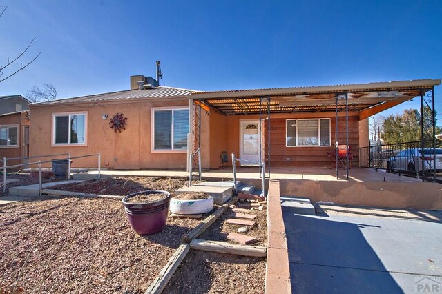 back of house with a standing seam roof, metal roof, and fence