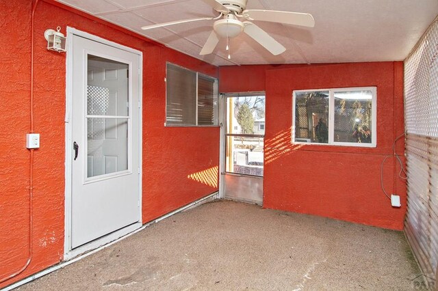 empty room featuring a textured wall and a ceiling fan