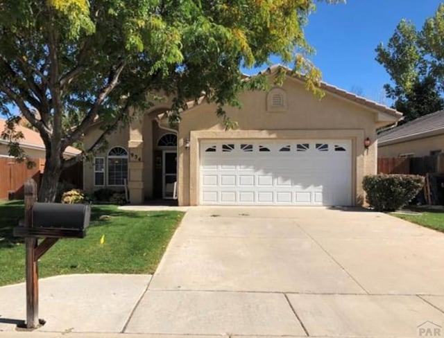 ranch-style house featuring a garage, driveway, stucco siding, fence, and a front yard