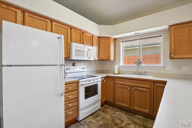 kitchen featuring light countertops, white appliances, brown cabinetry, and a sink