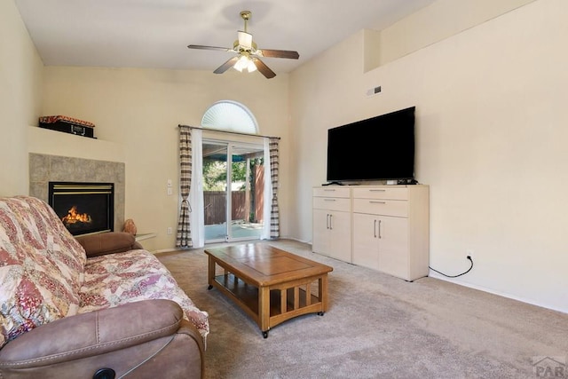 living room with a ceiling fan, vaulted ceiling, light colored carpet, and a fireplace