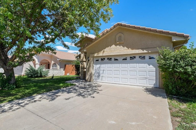 view of front of property featuring a tile roof, stucco siding, concrete driveway, a front yard, and a garage