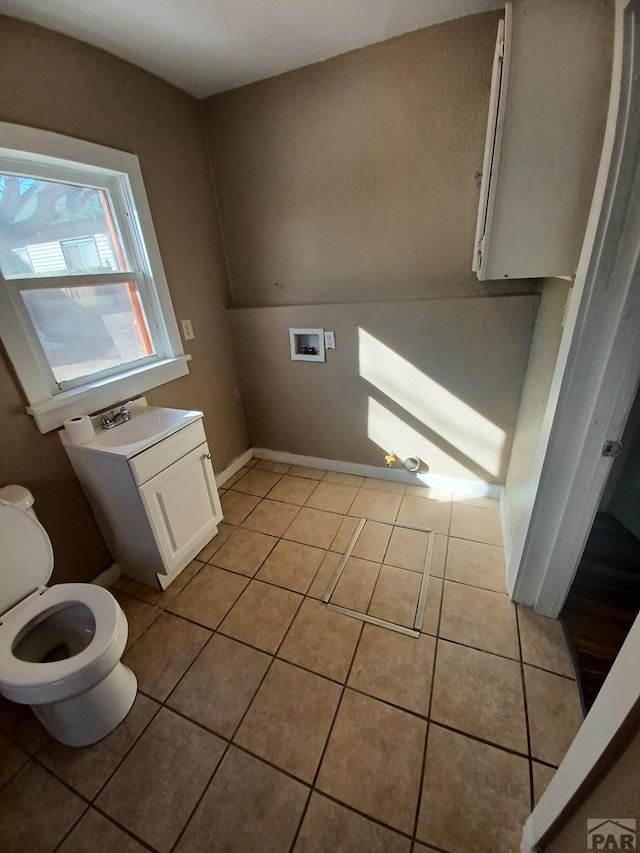 half bathroom with toilet, lofted ceiling, a sink, and tile patterned floors