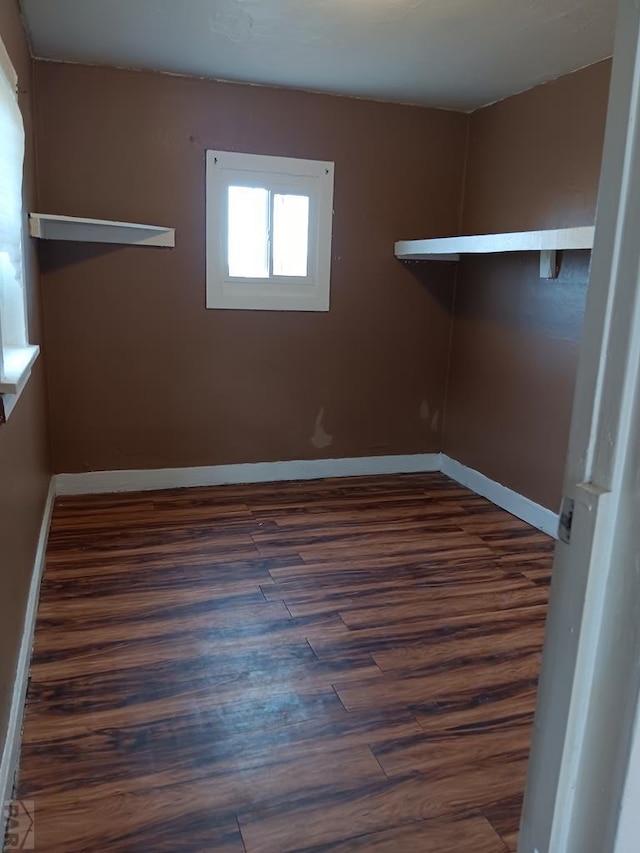 empty room featuring dark wood-type flooring and baseboards