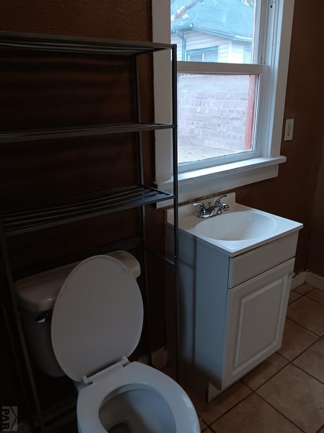 half bathroom with toilet, tile patterned flooring, and vanity