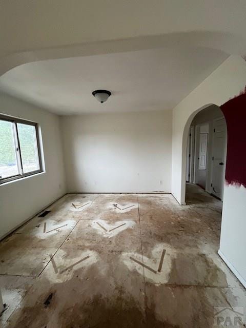 unfurnished room featuring arched walkways