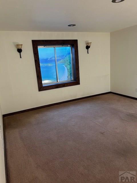 carpeted empty room featuring baseboards