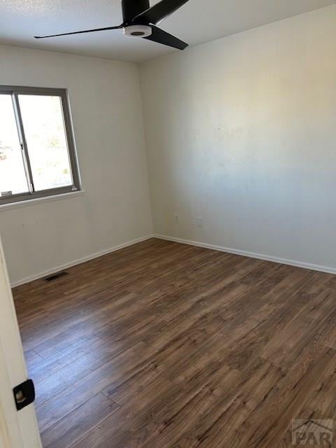 unfurnished room with a ceiling fan, baseboards, visible vents, and dark wood-type flooring