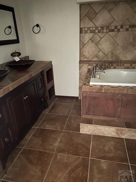 full bathroom featuring a garden tub, vanity, and tile patterned floors