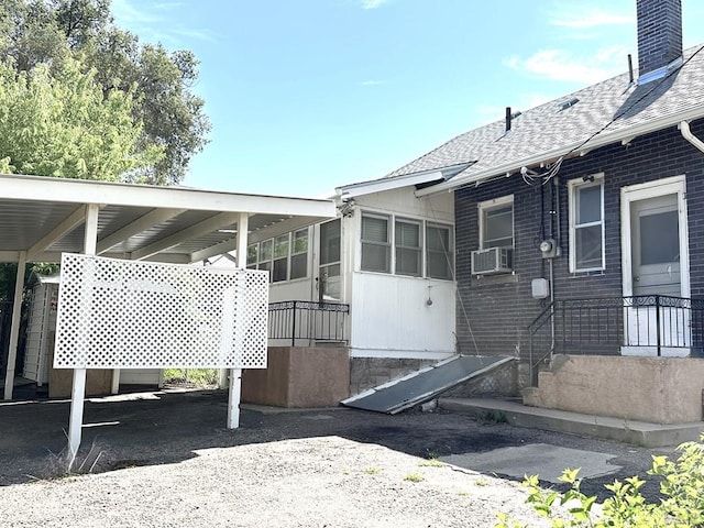 519 Broadway Ave, Pueblo, CO 81004 - rear view of house featuring an attached carport, cooling unit, brick siding, roof with shingles, and a chimney