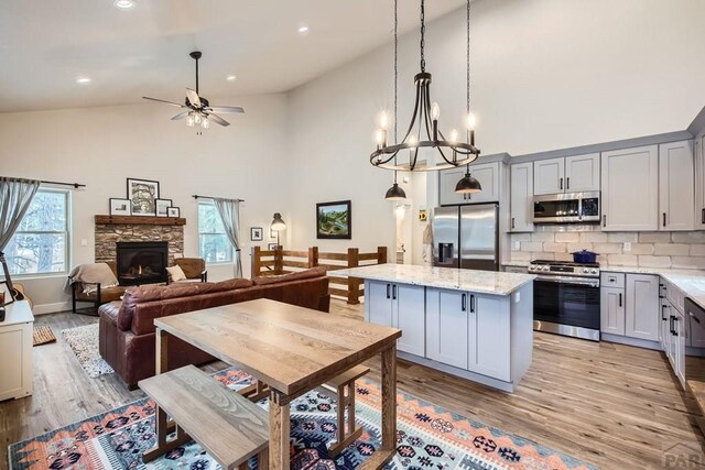 kitchen with a kitchen island, decorative light fixtures, light stone countertops, gray cabinets, and stainless steel appliances